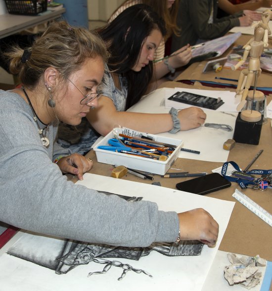 Several teens drawing from wooden figures