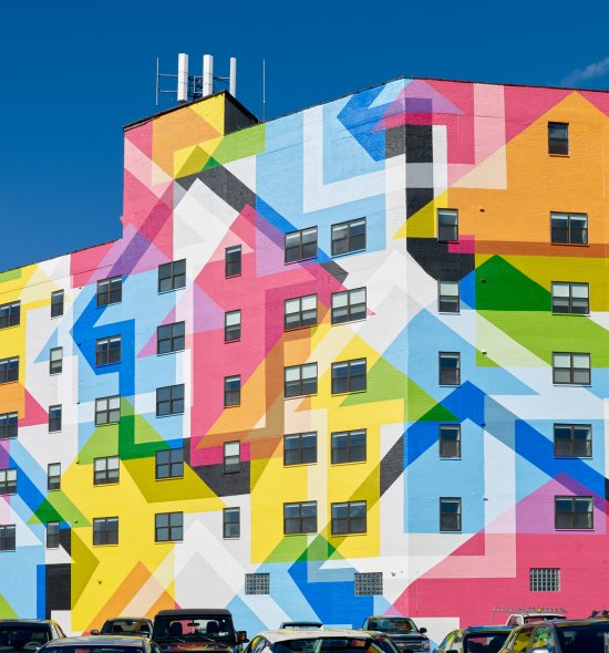 A large colorful mural with an upward arrow motif on the large exterior wall
