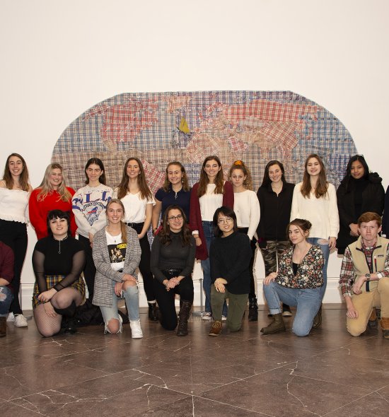 A group of teenagers standing in front of an artwork depicting a map of the world