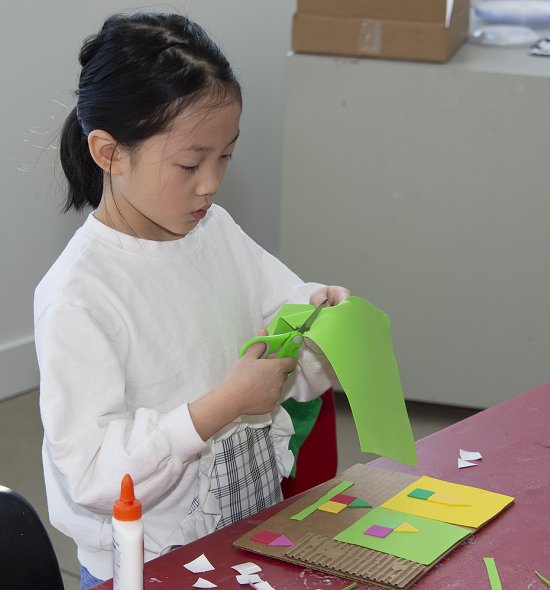 An Asian girl making a collage in a classroom
