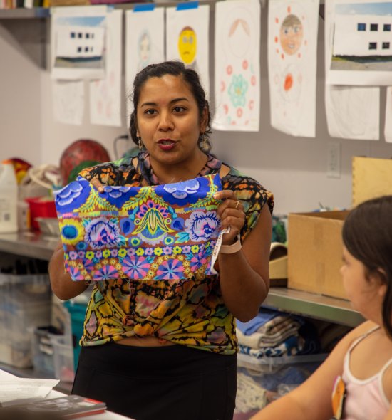 A person holding up a patterned piece of fabric in a studio