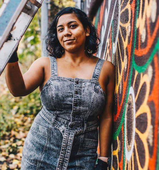 A woman leaning against a colorful painted wall