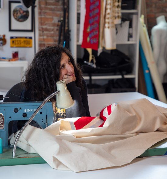 A woman with dark hair sitting at a sewing machine