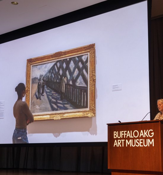 A person standing behind a podium presenting in front of a large screen