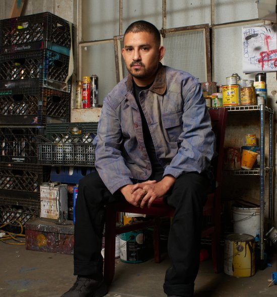 A person wearing a denim jacket sitting in an artist studio
