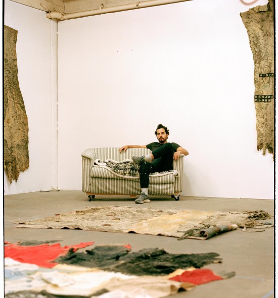 Film photo of a person in an open studio space sitting on a couch against a white wall
