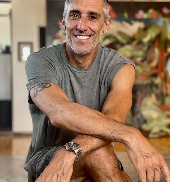 A person smiling with their arms crossed over their knee