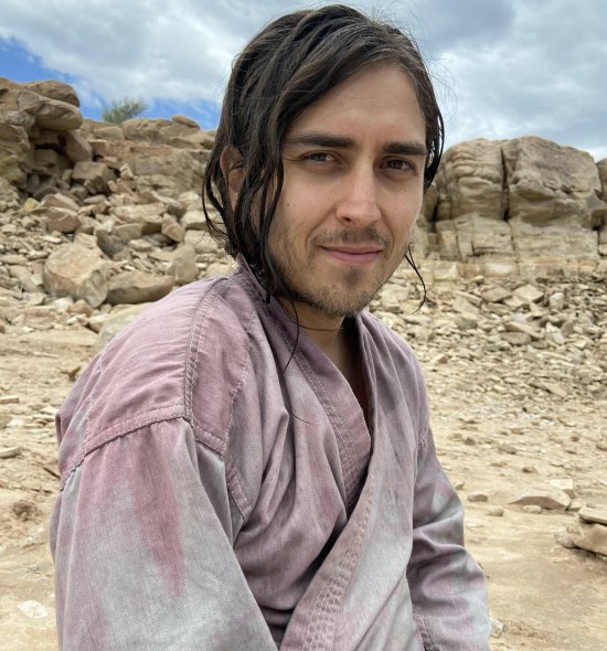 A person in a desert area smiling softly at the camera