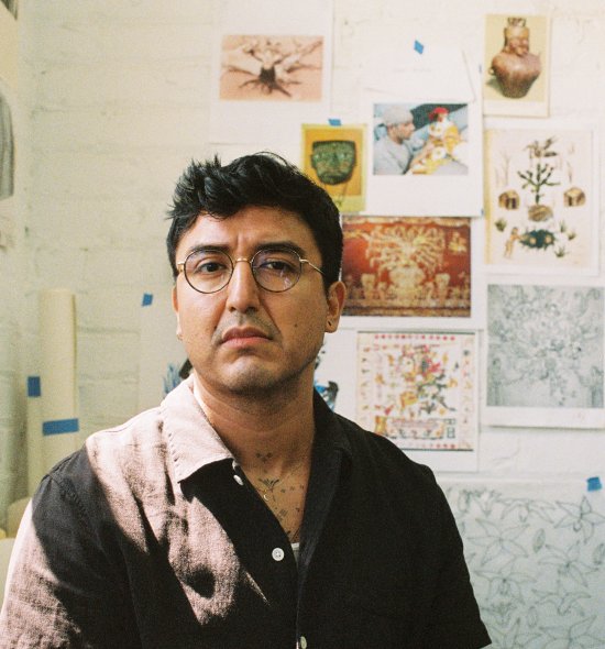 A person with dark hair and a brown button down shirt, wearing glasses, looking away from the camera