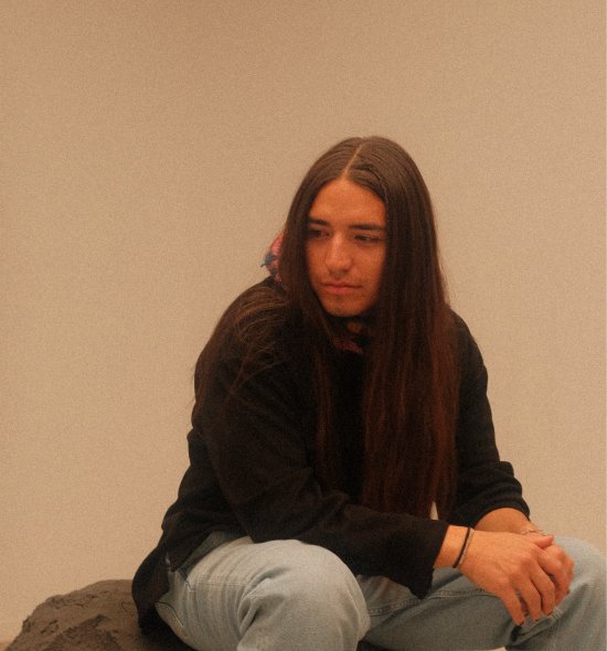 A person sitting on a rock in front of a beige background