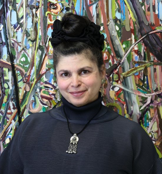 A person with dark hair pulled into an updo, standing in front of an abstract artwork