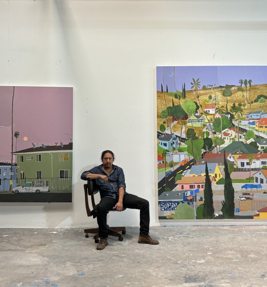 A person sitting in a roller chair in between two large paintings of neighborhoods