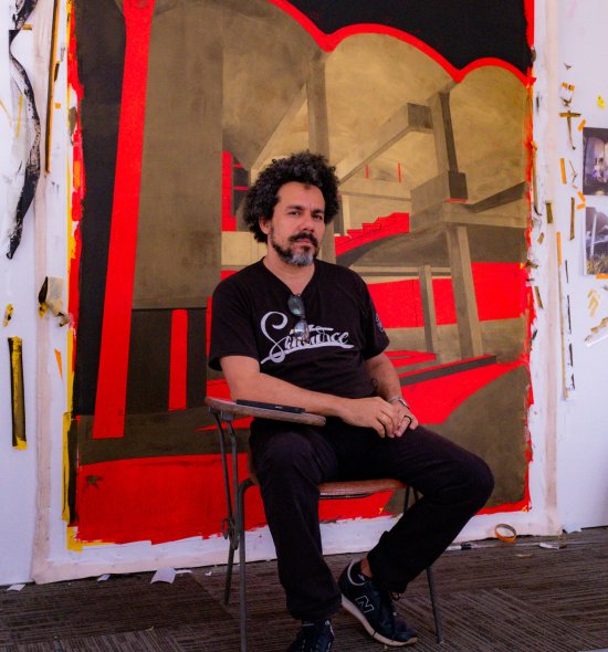 A person sitting in a chair in front of a large vibrant painting 