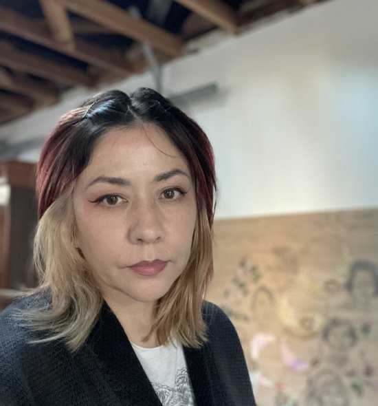 A person with multiple hair colors wearing a black blazer and white shirt