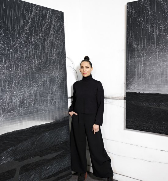 A person wearing all black standing in between two large black and white paintings