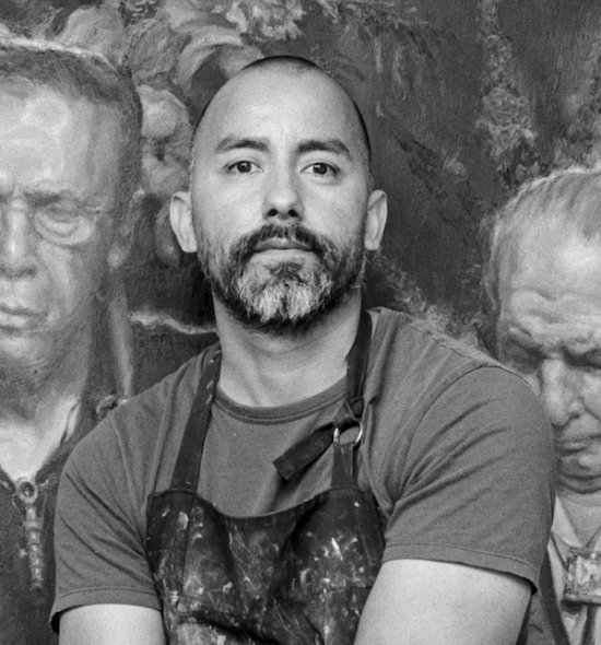 Black and white photo of a person wearing an apron, standing in front of a painting