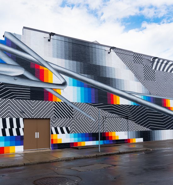 A large mural on an exterior wall featuring black and white stripes and blocks of color